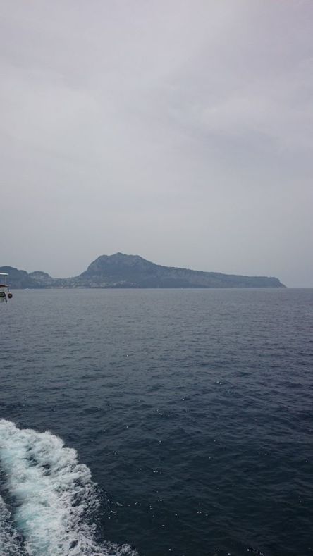 Capri from a distance. Monte Solaro is the highest peak to the right; the Blue Grotto is at sea level far right.